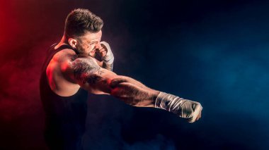 Sporcu Muay Thai boksörü siyah arka planda dumanla dövüşüyor. Spor konsepti