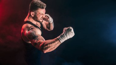 Sporcu Muay Thai boksörü siyah arka planda dumanla dövüşüyor. Spor konsepti