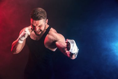 Sporcu Muay Thai boksörü siyah arka planda dumanla dövüşüyor. Spor konsepti