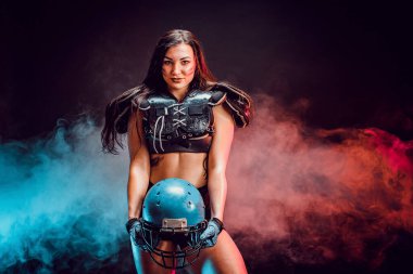 Genç esmer, rugby oyuncusu pozu veren seksi bir üniforma giyiyor.