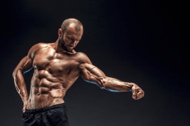 Mükemmel karın kasları, omuzları, pazıları, kol ve göğsü olan güçlü bir adam. Vücut geliştiren üstsüz siyah arka plan üzerinde kaslarını esnetiyor.