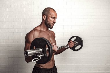 Vücut geliştirici pazılar için halterle egzersiz yapıyor.