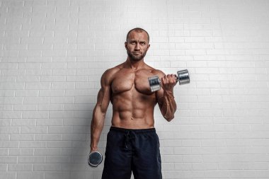 Vücut geliştirici, pazılar için iki kola karşı halterle egzersiz yapıyor.