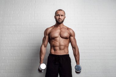 Vücut geliştirici, pazılar için iki kola karşı halterle egzersiz yapıyor.