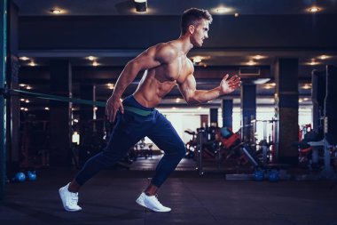 Genç bir sporcu direniş bandıyla egzersiz yapıyor.