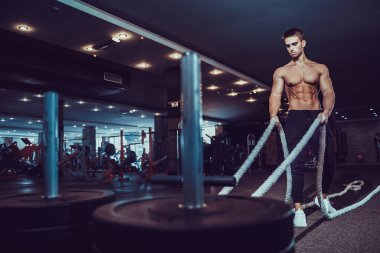 Fitness adamı spor salonunda halatlarla çalışıyor.