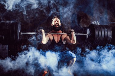 Modern fitness merkezinde kaslı bir fitness adamı halterle kafasına halteri indiriyor. Fonksiyonel eğitim.