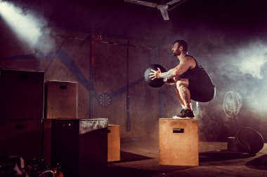 Sporcu egzersiz yaptı. Kutunun üstüne atlamak. İniş aşaması. Koyu tonda jimnastik atışları. İç..