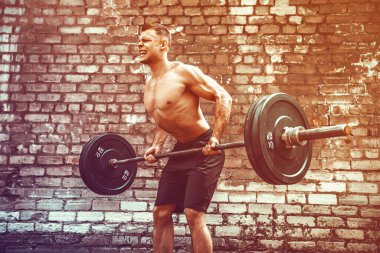 Atletik bir adam halterle çalışıyor. Kuvvet ve motivasyon