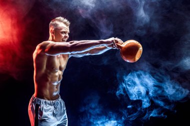 Kettlebell ile egzersiz yapan konsantre kaslı adam.