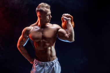 Kettlebell ile egzersiz yapan konsantre kaslı adam.