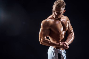 Stüdyoda poz veren yakışıklı güçlü vücut geliştirici.