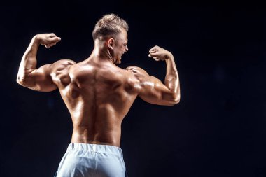 Stüdyoda poz veren yakışıklı güçlü vücut geliştirici.