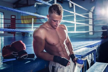 Yakışıklı genç kaslı sporcu dinlenirken su içiyor.