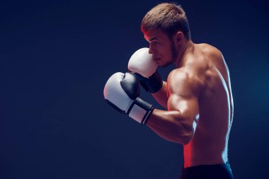 Siyah arka planda eldivenli üstsüz boksör.