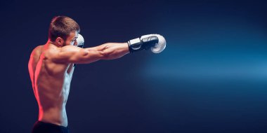 Siyah arka planda eldivenli üstsüz boksör.