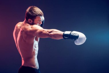 Siyah arka planda eldivenli üstsüz boksör.