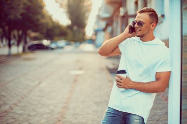 Alışveriş merkezinin yakınında bir fincan kahve ve akıllı telefonlu yakışıklı bir adam. Arkadaşımı bekliyorum.