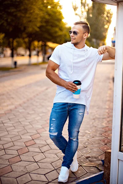 Alışveriş merkezinin yakınında bir fincan kahve ve akıllı telefonlu yakışıklı bir adam. Arkadaşımı bekliyorum.