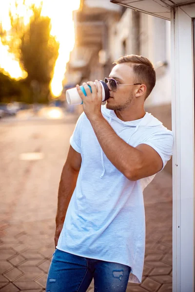 Alışveriş merkezinin yakınında bir fincan kahve ve akıllı telefonlu yakışıklı bir adam. Arkadaşımı bekliyorum.