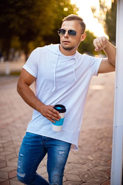 Alışveriş merkezinin yakınında bir fincan kahve ve akıllı telefonlu yakışıklı bir adam. Arkadaşımı bekliyorum.