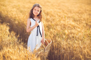 Gün batımı buğday tarlasında yürüyen küçük kız