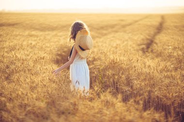 Gün batımı buğday tarlasında yürüyen küçük kız