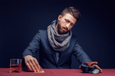 Siyah kumarhanede oynayan, puro içen, viski içen şık sakallı adam.