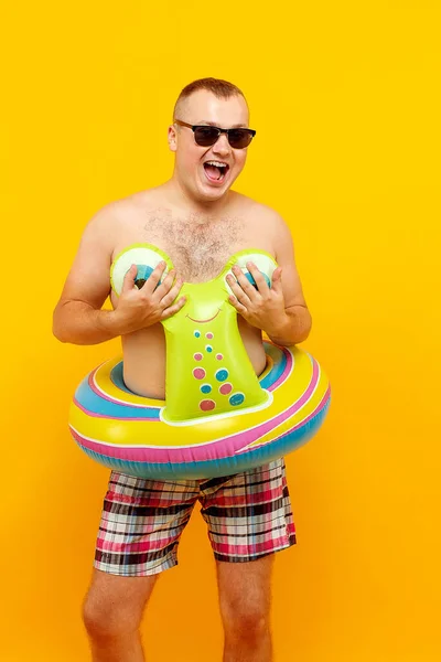 Hombre en topless adulto en forma de anillo de goma de caracol y gafas de sol posando sobre fondo amarillo. Aislar —  Fotos de Stock