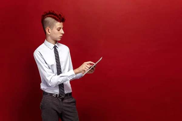 Punk elegante com tablet contra de fundo vermelho — Fotografia de Stock