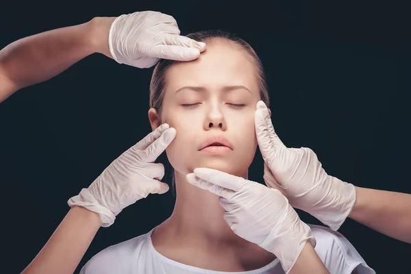 Junge Frau mit geschlossenen Augen bei einer Untersuchung ihrer Gesichtshaut durch plastische Ärzte — Stockfoto