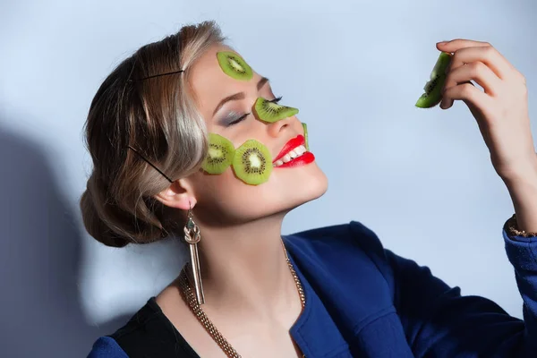 Foto fashion wanita berpose dengan irisan kiwi di wajahnya — Stok Foto