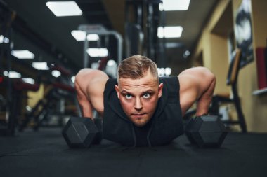 Spor salonunda şınav çeken genç bir sporcu. Kaslı ve güçlü adam egzersiz yapıyor.