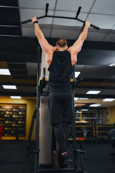 Homem no ginásio fazendo exercícios na barra transversal no ginásio — Fotografia de Stock