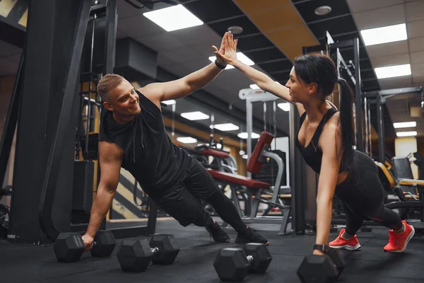 Δυνατό και όμορφο αθλητικό ζευγάρι γυμναστικής σε ρούχα γυμναστικής κάνει push up ασκήσεις και δίνοντας ο ένας τον άλλο ένα υψηλό πέντε — Φωτογραφία Αρχείου