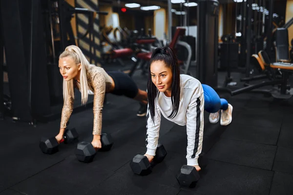 Zdrowy styl życia. Portret dwóch młodych sportowców robiących deskę na siłowni. — Zdjęcie stockowe