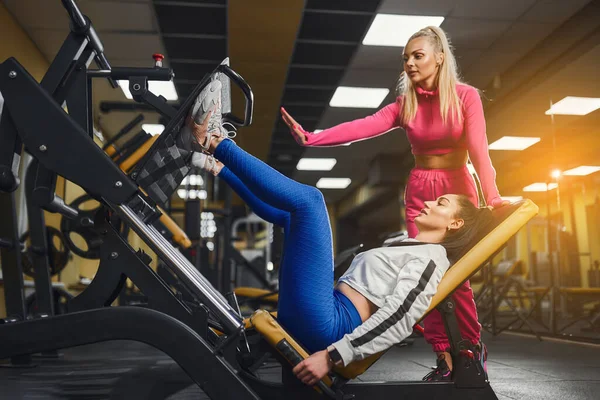Προσωπικός γυμναστής βοηθά τη γυναίκα στο workout σε συσκευές κατάρτισης μέσα στο γυμναστήριο. Αθλητικός τρόπος ζωής, bodybuilding, εκπαίδευση έννοια — Φωτογραφία Αρχείου