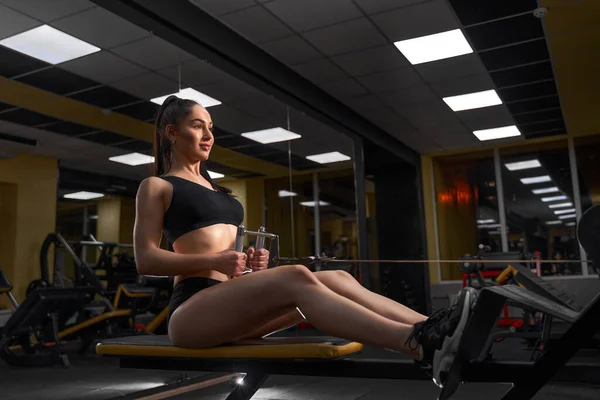 Musculaire fitness vrouw atleet doet zware gewicht oefening voor terug op de machine met kabel in de sportschool — Stockfoto