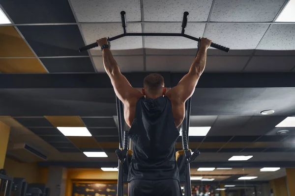 Hombre en el gimnasio haciendo ejercicios en la barra transversal en el gimnasio —  Fotos de Stock