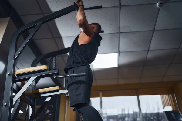 Hombre en el gimnasio haciendo ejercicios en la barra transversal en el gimnasio —  Fotos de Stock