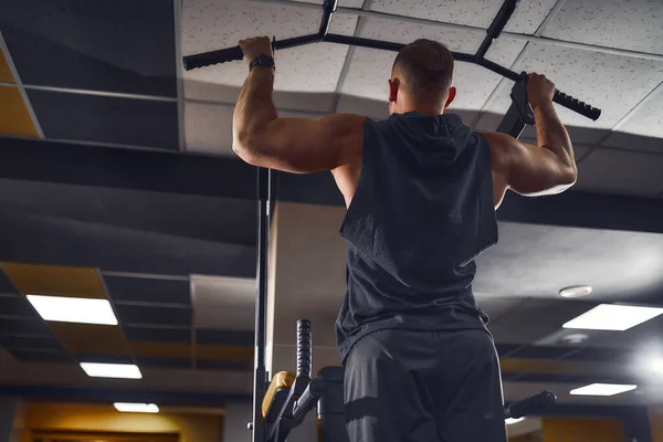 Hombre en el gimnasio haciendo ejercicios en la barra transversal en el gimnasio —  Fotos de Stock