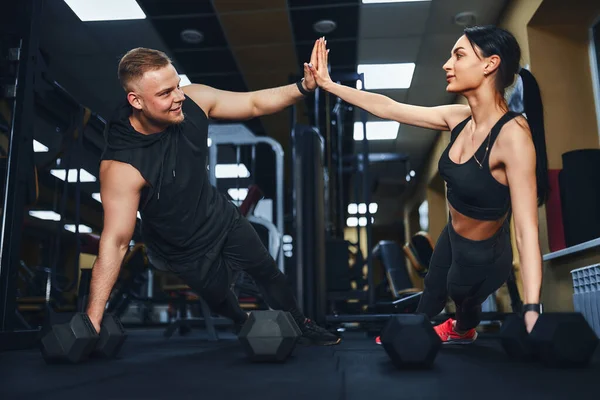 Δυνατό και όμορφο αθλητικό ζευγάρι γυμναστικής σε ρούχα γυμναστικής κάνει push up ασκήσεις και δίνοντας ο ένας τον άλλο ένα υψηλό πέντε — Φωτογραφία Αρχείου