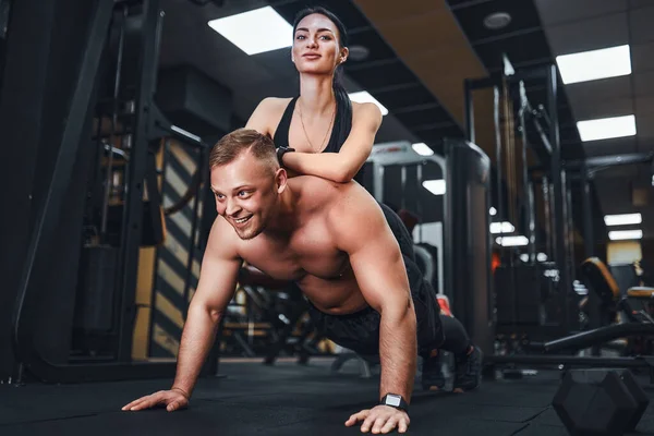 Young muscular man doing push-up exercise and holding girl. joint training. Group lessons. Teambuilding. romance. — Stock Photo, Image