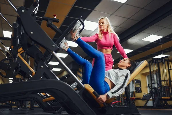 Personal Trainer hilft Frau beim Training an Trainingsgeräten im Fitnessstudio. Sportlicher Lebensstil, Bodybuilding, Trainingskonzept — Stockfoto