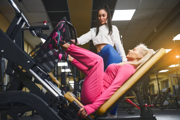 Προσωπικός γυμναστής βοηθά τη γυναίκα στο workout σε συσκευές κατάρτισης μέσα στο γυμναστήριο. Αθλητικός τρόπος ζωής, bodybuilding, εκπαίδευση έννοια — Φωτογραφία Αρχείου