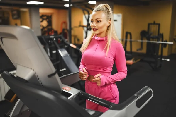 Молодая здоровая блондинка кардио на беговой дорожке в спортзале — стоковое фото