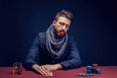 Siyah kumarhanede oynayan, puro içen, viski içen şık sakallı adam.