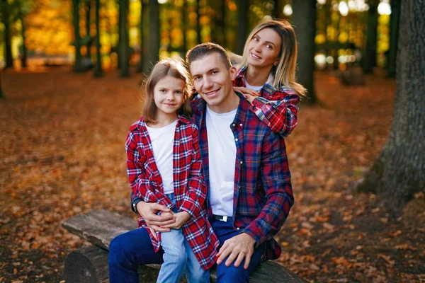 Bilde av en flott familie i høstskogen på en benk – stockfoto