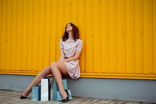 Stijlvolle vrouw op een shopping tour in de stad, het dragen van gekochte items in papieren tassen. — Stockfoto