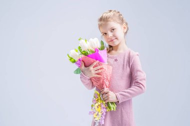 Bir buket beyaz lalesi olan güzel küçük bir kız.